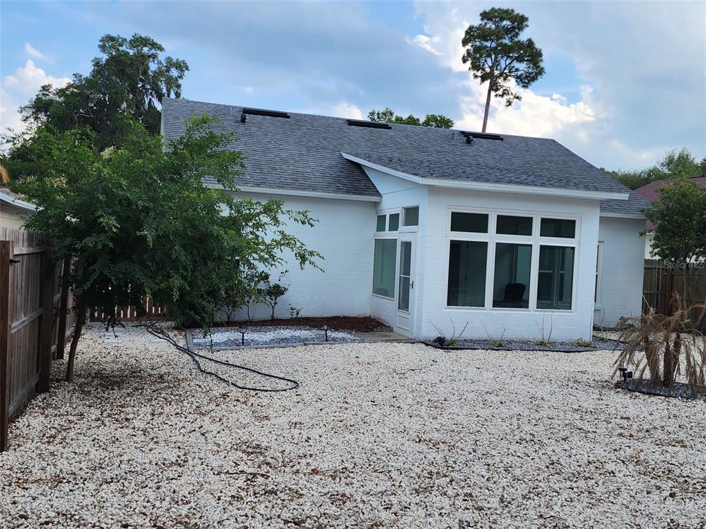 The exterior of a white house features a gravel yard, a tree, and large windows — 327 HERITAGE ESTATES LANE, DELAND, FL
