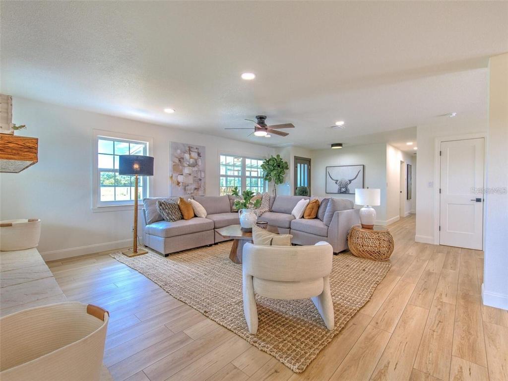 A living room features a gray sectional sofa, a jute rug, and light wood flooring — 4608 HOLBROOK ROAD, PLANT CITY, FL