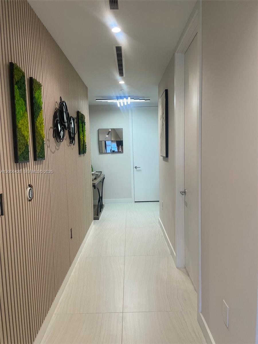 A hallway features light-colored tile flooring, a slatted wood wall, and modern light fixtures — 220 SE Mizner Blvd # 321, Boca Raton FL 33432, BOCA RATON, FL