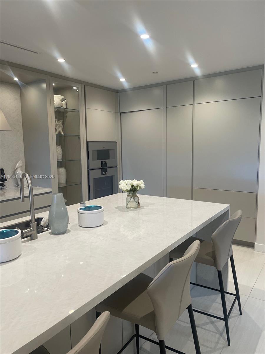 A modern kitchen features a large white stone island, gray cabinetry, and integrated appliances — 220 SE Mizner Blvd # 321, Boca Raton FL 33432, BOCA RATON, FL