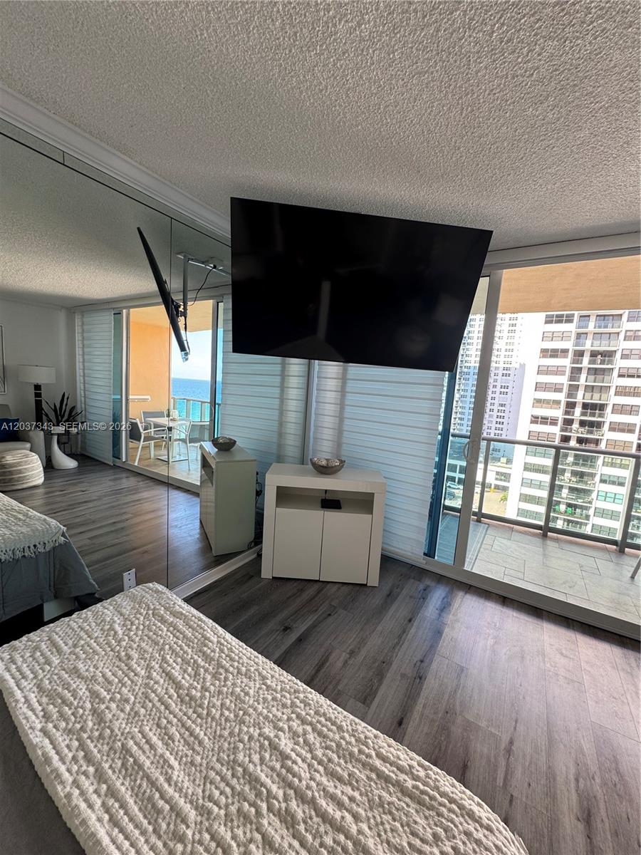 A bedroom features wood-look flooring, a wall-mounted television, mirrored walls, and a balcony with ocean views — 2501 S Ocean Dr # 1105, Hollywood FL 33019, HOLLYWOOD, FL