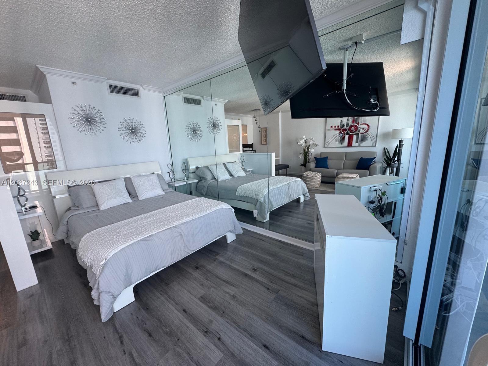 A bedroom features a bed, mirrored wall, and a television mounted on a ceiling bracket — 2501 S Ocean Dr # 1105, Hollywood FL 33019, HOLLYWOOD, FL