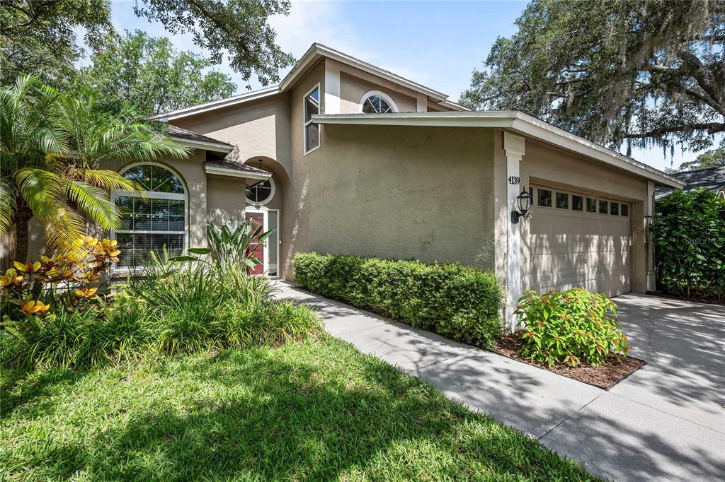 A tan stucco house with a two-car garage, arched windows, and a landscaped front yard — 4139 MORELAND DRIVE, VALRICO, FL
