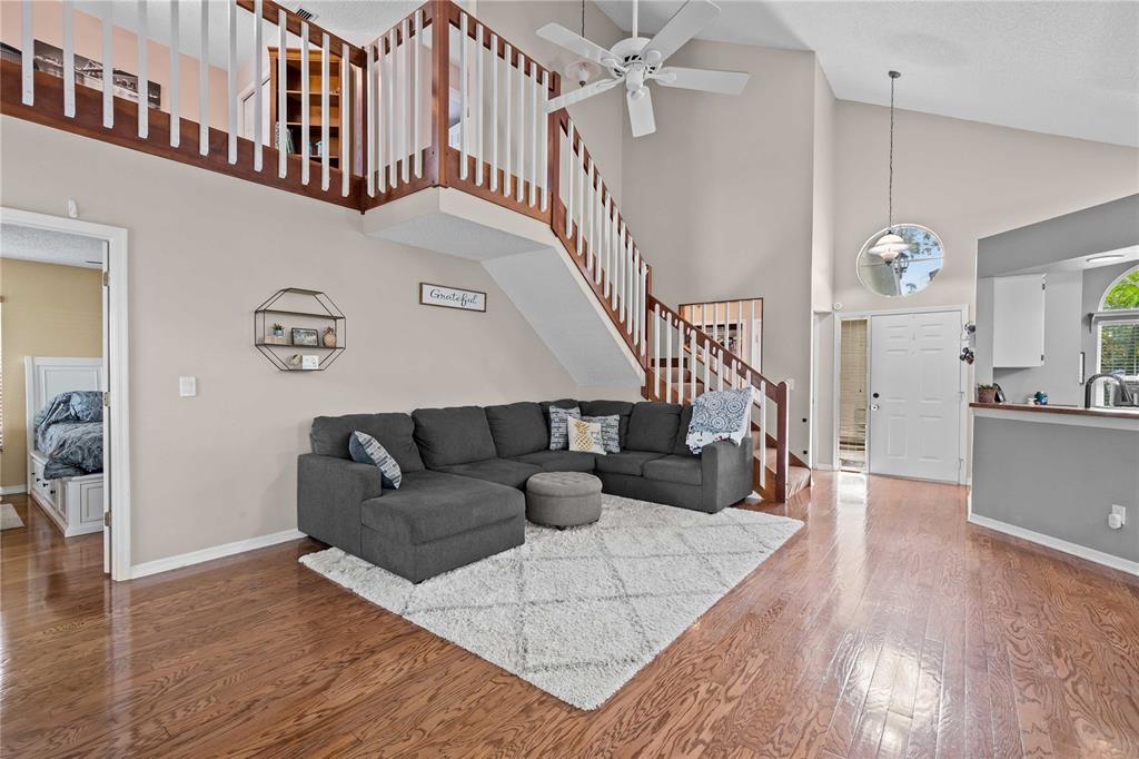 A living room with hardwood floors, a gray sectional sofa, and an open staircase — 4139 MORELAND DRIVE, VALRICO, FL