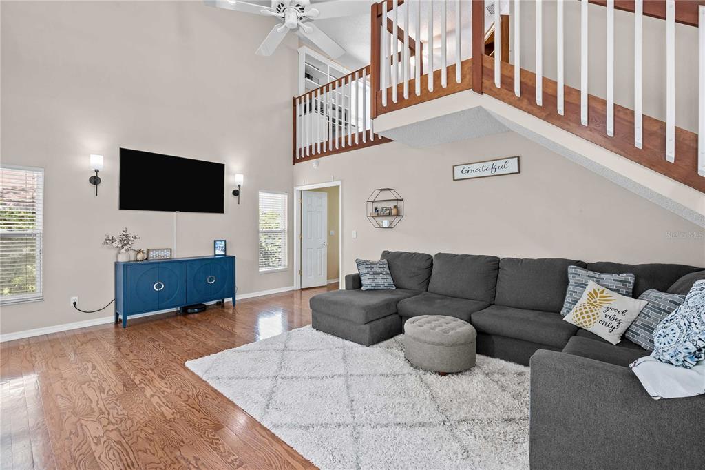 A living room features a vaulted ceiling, a gray sectional sofa, and a wooden staircase — 4139 MORELAND DRIVE, VALRICO, FL