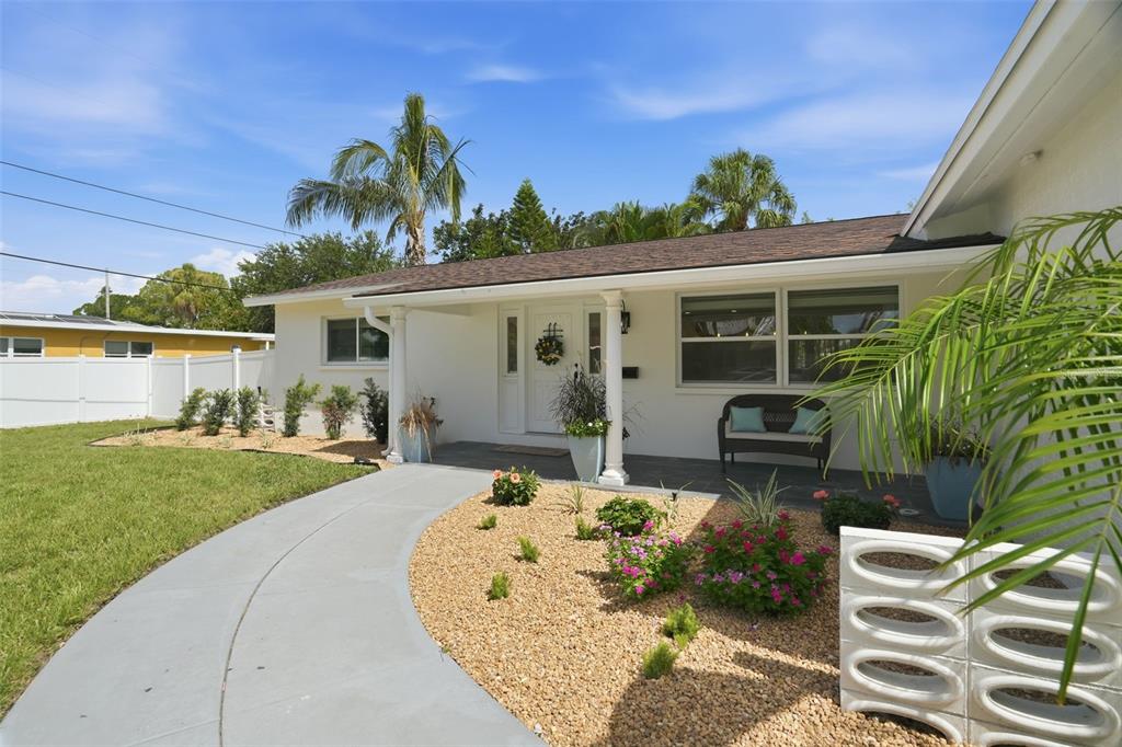 A white house with a curved concrete walkway, gravel landscaping, and a covered front porch — 1819 MARYLAND AVENUE NE, ST PETERSBURG, FL