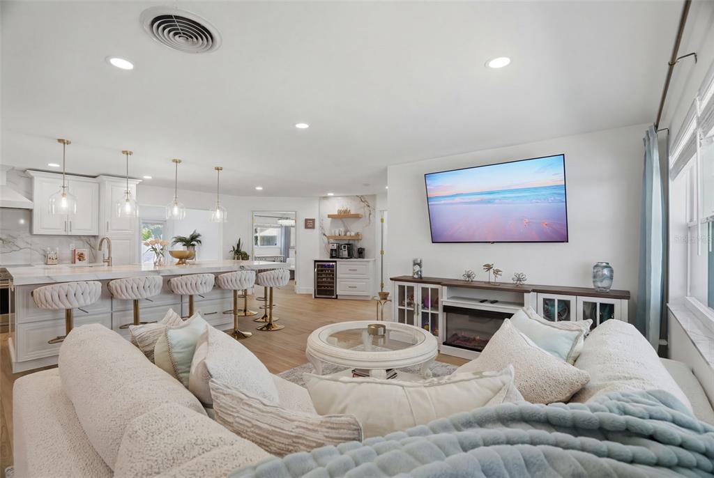 A bright open-concept living room and kitchen featuring white cabinetry, marble countertops, and a television — 1819 MARYLAND AVENUE NE, ST PETERSBURG, FL