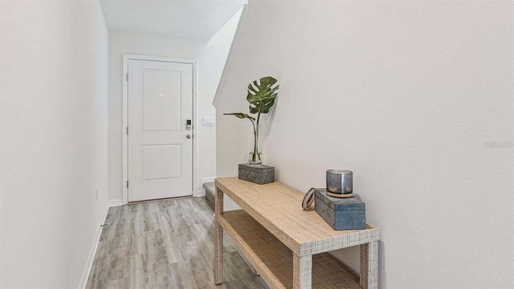 A light-filled entryway features wood-look flooring, a white door, and a wooden console table — 2346 AVEENO AVENUE, HAINES CITY, FL