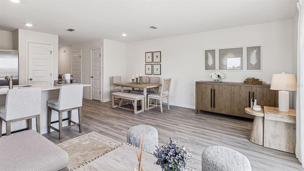 A bright open-concept living and dining area features light wood flooring and neutral furniture — 2346 AVEENO AVENUE, HAINES CITY, FL
