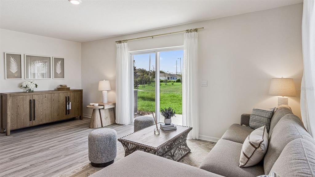 A living room features a gray sectional sofa, a wooden console, and sliding glass doors — 2346 AVEENO AVENUE, HAINES CITY, FL