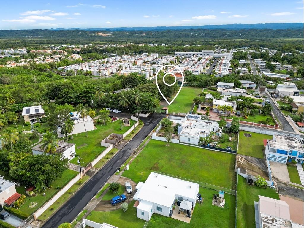 An aerial view shows a residential neighborhood with a marked vacant lot and houses — 690 LOS NABORIAS STREET, VEGA ALTA, PR