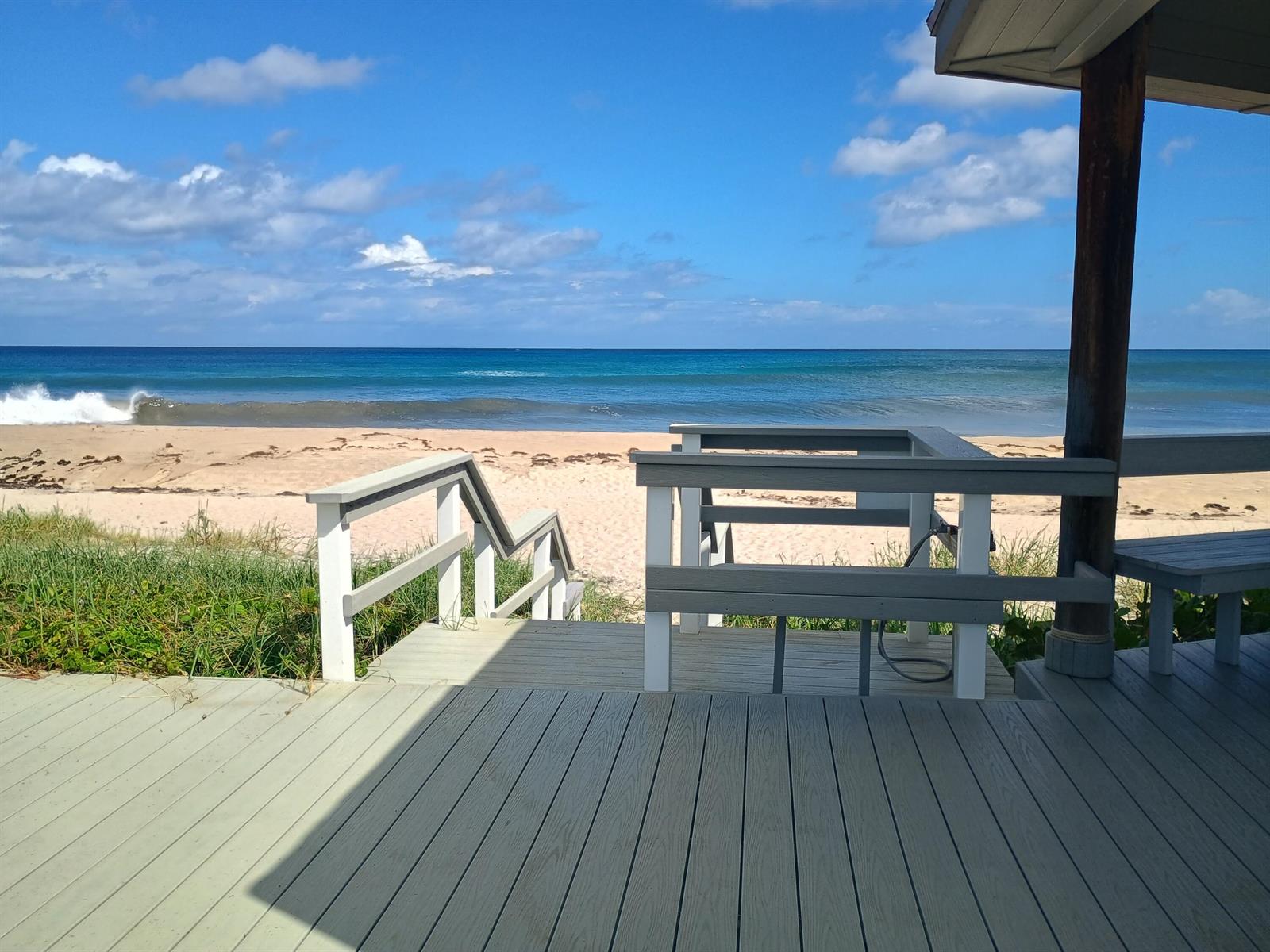 A wooden deck with stairs leads directly to a sandy beach and the ocean — 5505 N Ocean Boulevard # 106, Ocean Ridge FL 33435, OCEAN RIDGE, FL