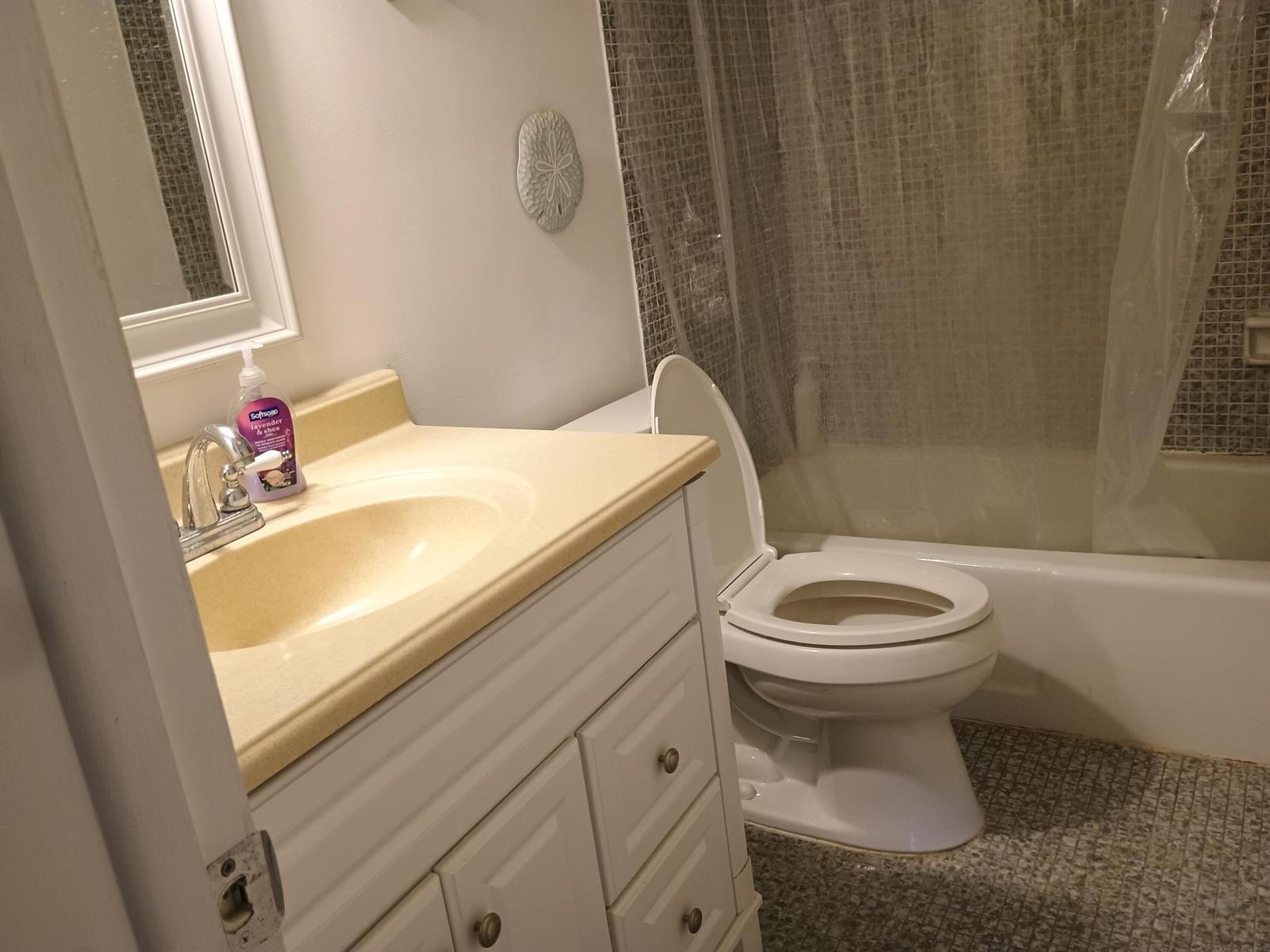 A bathroom features a white vanity with a beige countertop, a toilet, and a shower-tub combo — 5505 N Ocean Boulevard # 106, Ocean Ridge FL 33435, OCEAN RIDGE, FL
