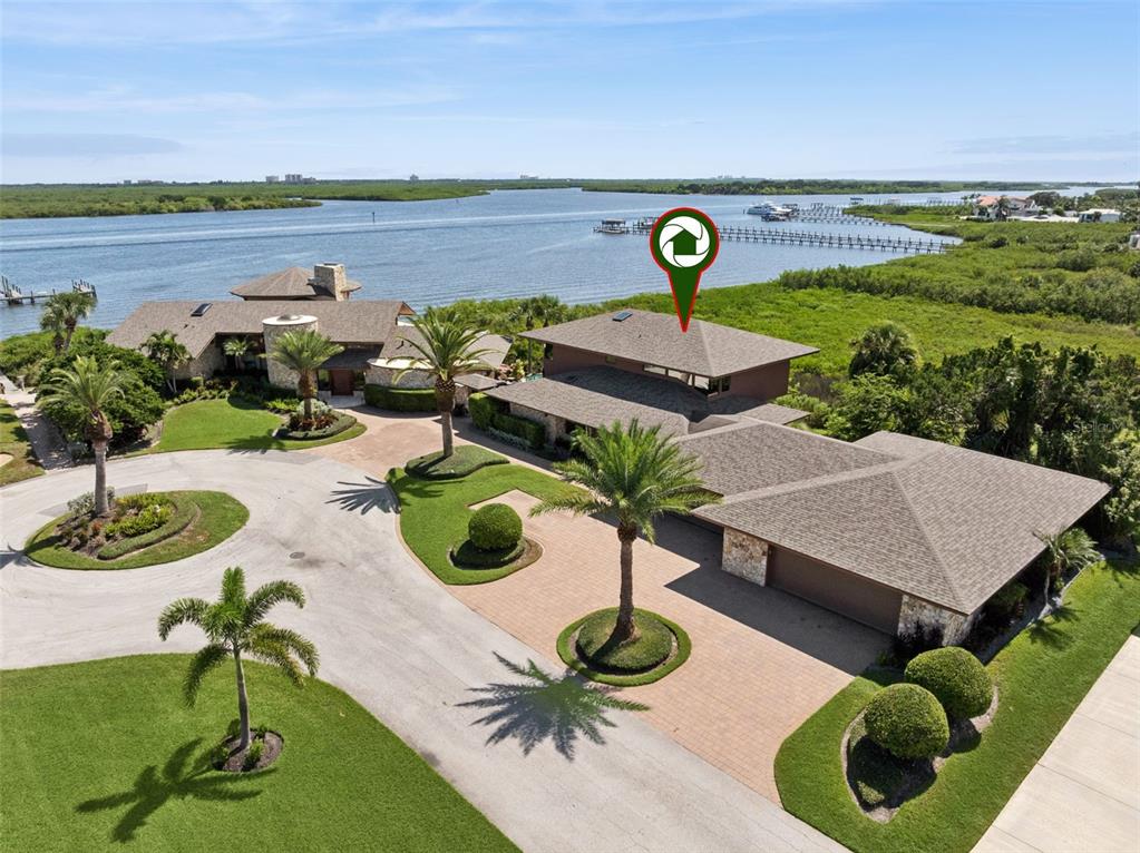 An aerial view of a large waterfront house with a circular driveway and palm trees — 107 DONLON DRIVE, NEW SMYRNA BEACH, FL