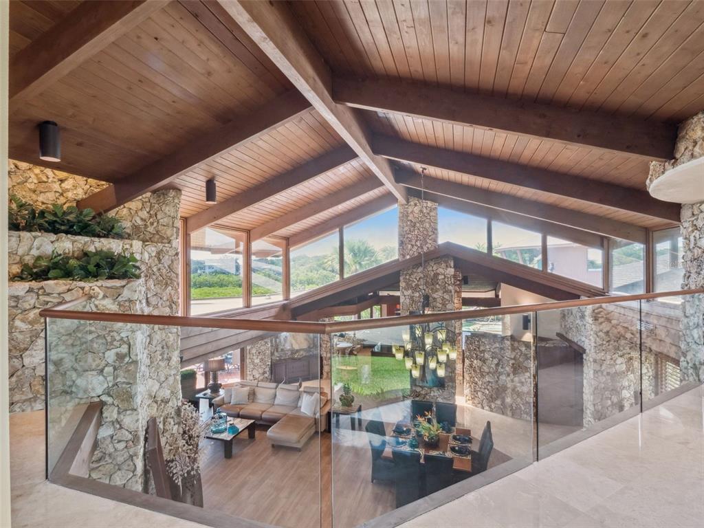 A high-angle view of a living and dining area with stone walls and vaulted ceilings — 107 DONLON DRIVE, NEW SMYRNA BEACH, FL