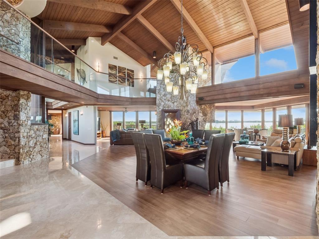 A spacious open-concept living and dining area features vaulted wood ceilings, stone walls, and windows — 107 DONLON DRIVE, NEW SMYRNA BEACH, FL
