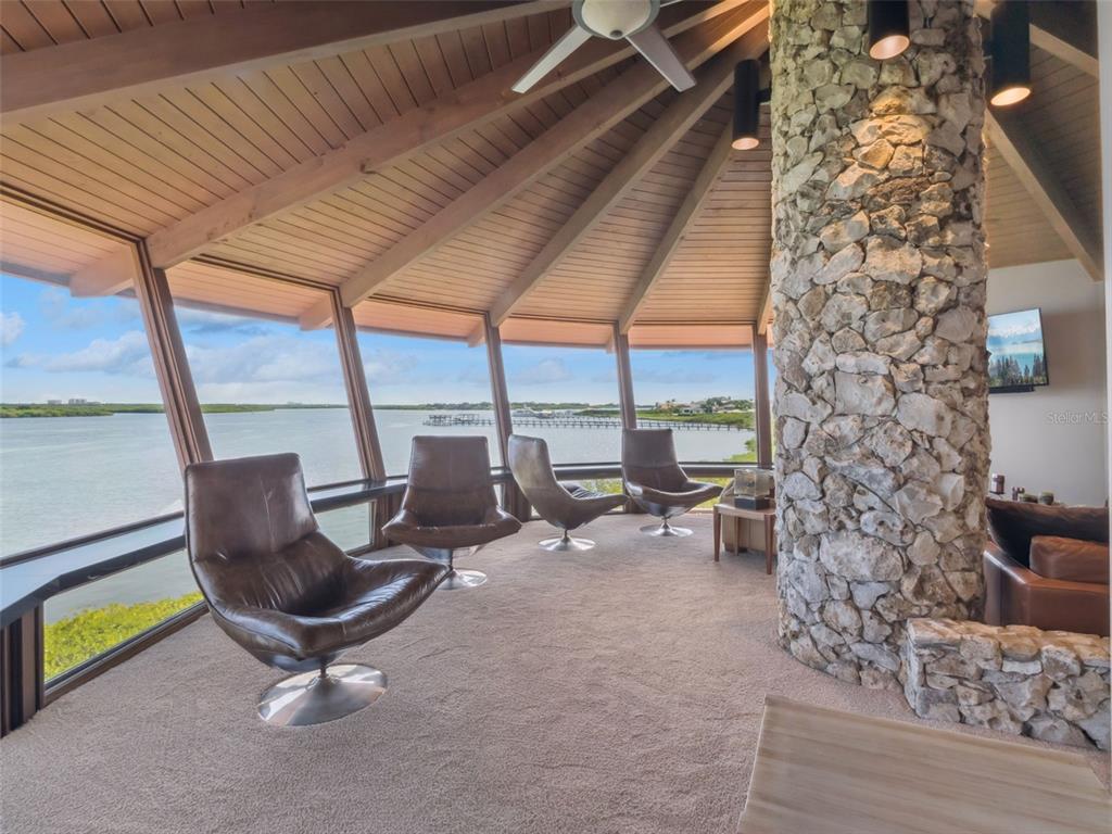 A sunroom with a stone pillar, carpeted floor, and floor-to-ceiling windows overlooking the water — 107 DONLON DRIVE, NEW SMYRNA BEACH, FL