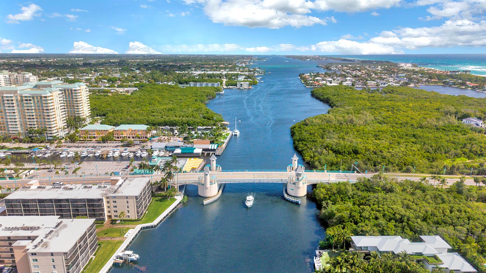 An aerial view shows a drawbridge over a waterway surrounded by buildings and dense vegetation — 9960 Pineapple Tree Drive # 109, Boynton Beach FL 33436, BOYNTON BEACH, FL
