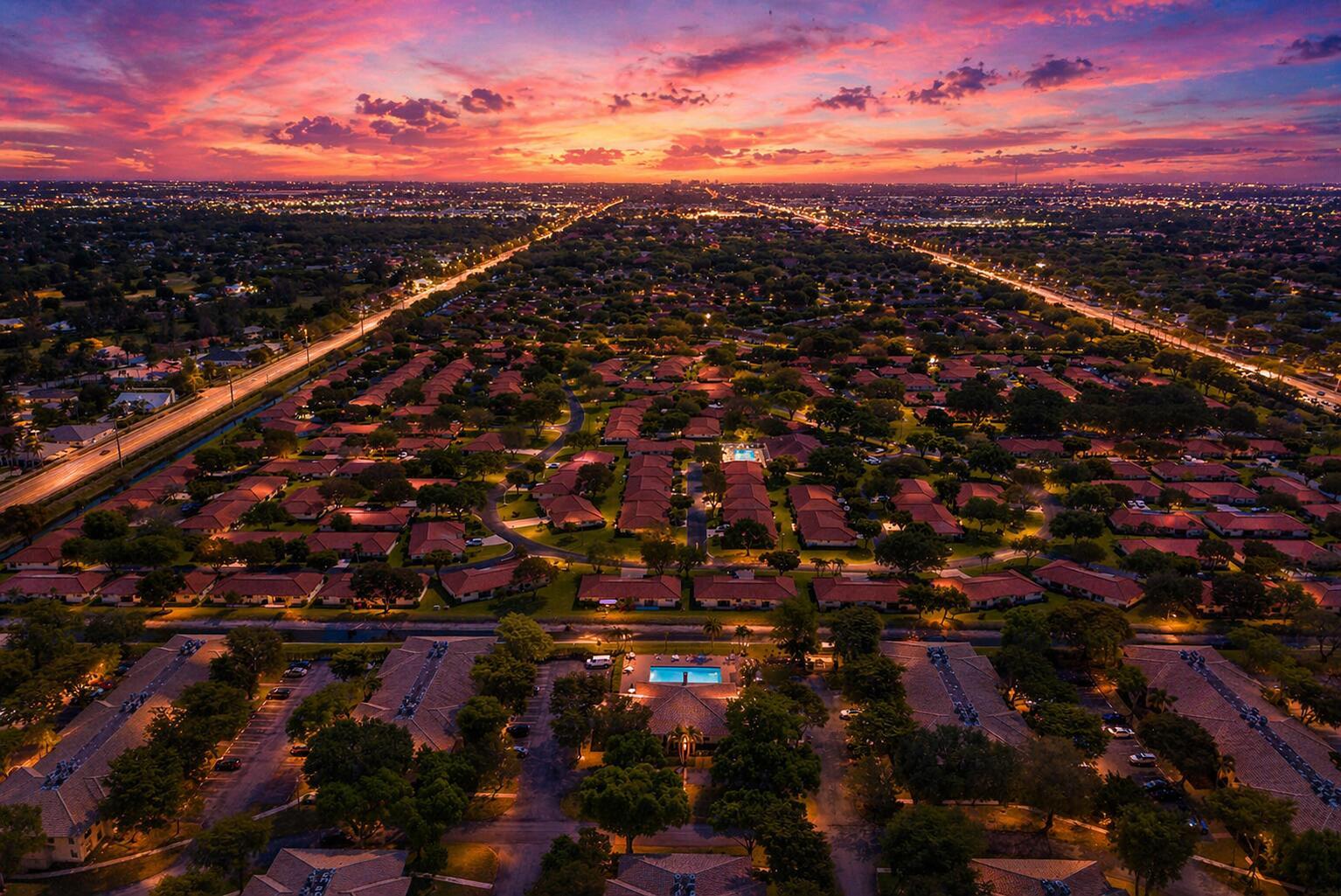 Aerial view of a residential neighborhood at sunset with a central swimming pool and roads — 9960 Pineapple Tree Drive # 109, Boynton Beach FL 33436, BOYNTON BEACH, FL