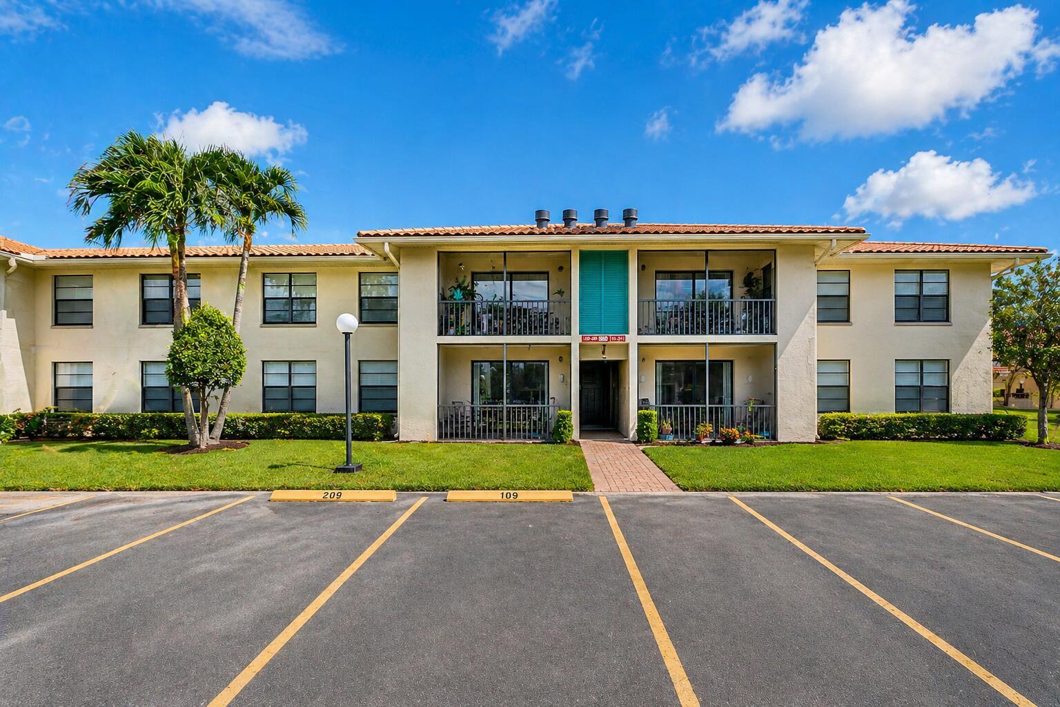 A two-story apartment building with a tiled roof, screened balconies, and a parking lot — 9960 Pineapple Tree Drive # 109, Boynton Beach FL 33436, BOYNTON BEACH, FL
