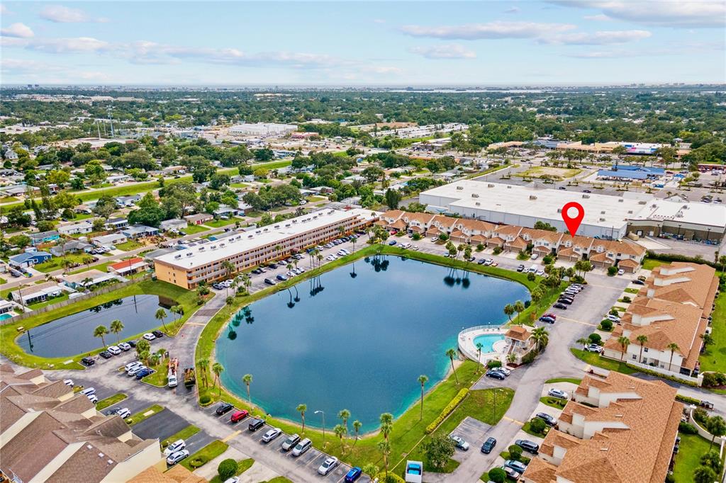 An aerial view shows a residential complex with townhomes surrounding a central lake — 6400 46TH AVENUE N UNIT 16, KENNETH CITY, FL
