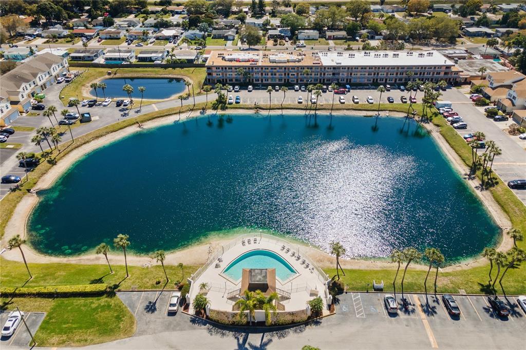 An aerial view shows a large lake, a swimming pool, and surrounding apartment buildings — 6400 46TH AVENUE N UNIT 16, KENNETH CITY, FL