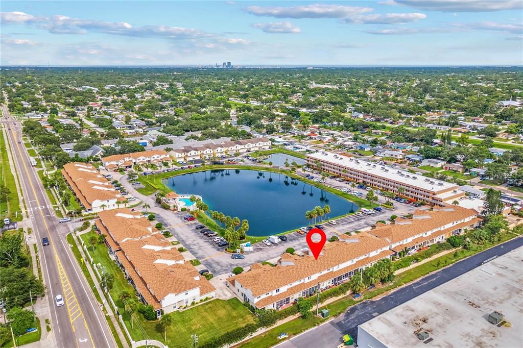An aerial view shows a residential complex with a central lake and a red pin — 6400 46TH AVENUE N UNIT 16, KENNETH CITY, FL