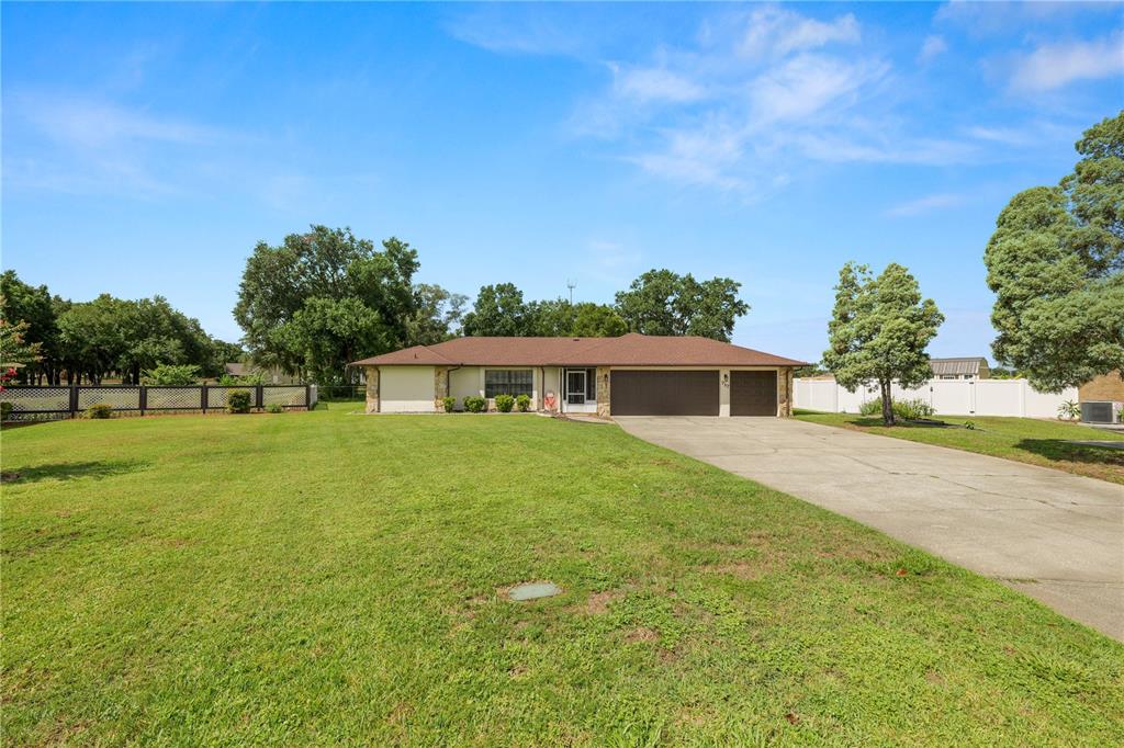A single-story house with a brown roof, stone accents, and a large concrete driveway — 717 CEDAR KNOLL DRIVE S, LAKELAND, FL