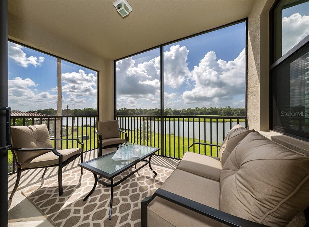 A screened-in patio features outdoor furniture and a view of a lake and trees — 16904 VARDON TERRACE UNIT 202, LAKEWOOD RANCH, FL