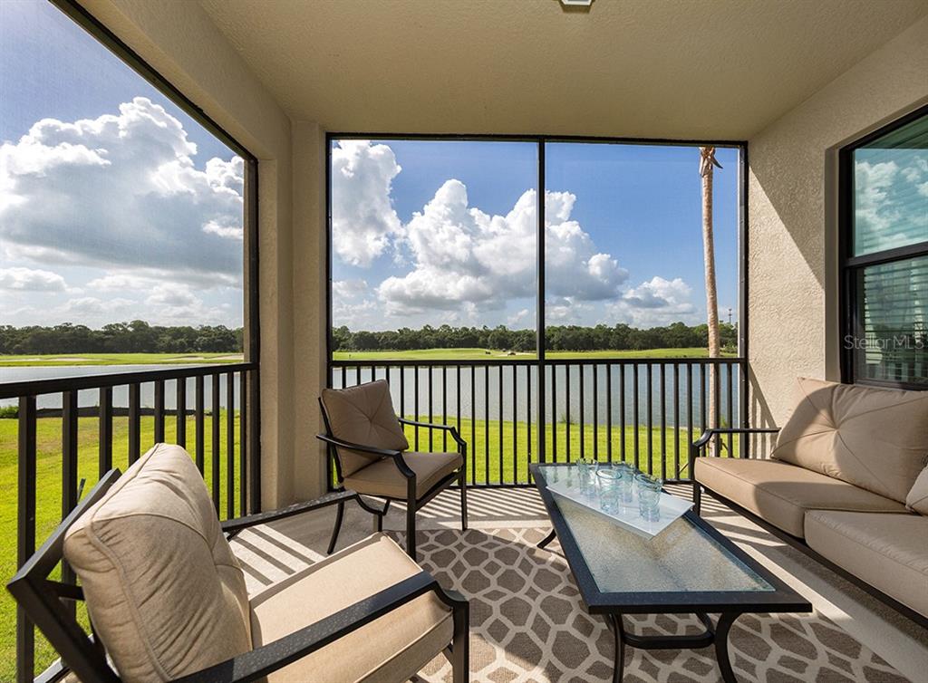 A screened-in patio features outdoor furniture overlooking a lake and a golf course — 16904 VARDON TERRACE UNIT 202, LAKEWOOD RANCH, FL