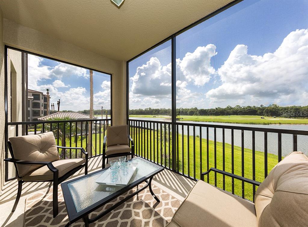 A screened-in balcony features patio furniture overlooking a lake and a golf course — 16904 VARDON TERRACE UNIT 202, LAKEWOOD RANCH, FL
