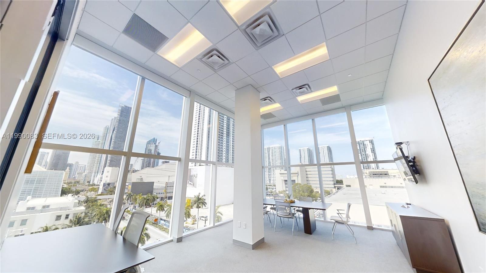 A bright office space features floor-to-ceiling windows with city views and a conference table — 1501 Biscayne Blvd # 5C, Miami FL 33132, MIAMI, FL