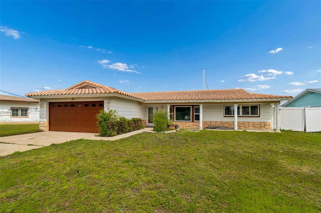 A single-story house with a brown garage door, tiled roof, and stone exterior accents — 15 BELLEVUE DRIVE, TREASURE ISLAND, FL