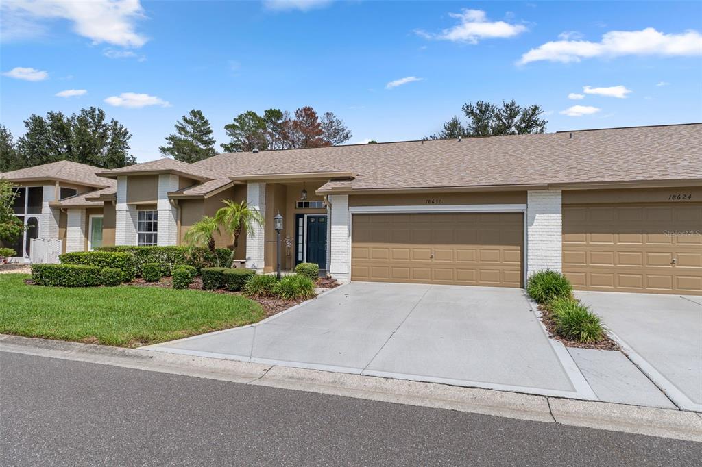The exterior of a single-story house features a two-car garage and a paved driveway — 18630 BENT PINE DRIVE, HUDSON, FL