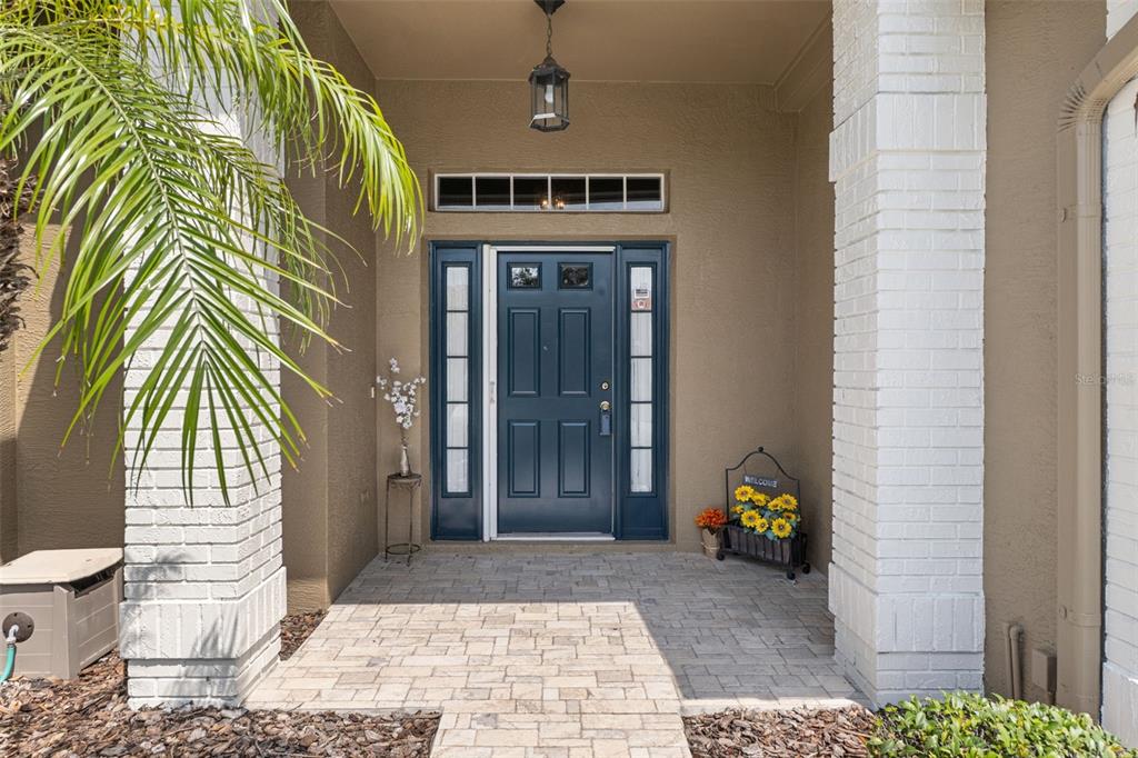 A front entryway features a dark blue door with sidelights, a brick-paved porch, and white pillars — 18630 BENT PINE DRIVE, HUDSON, FL