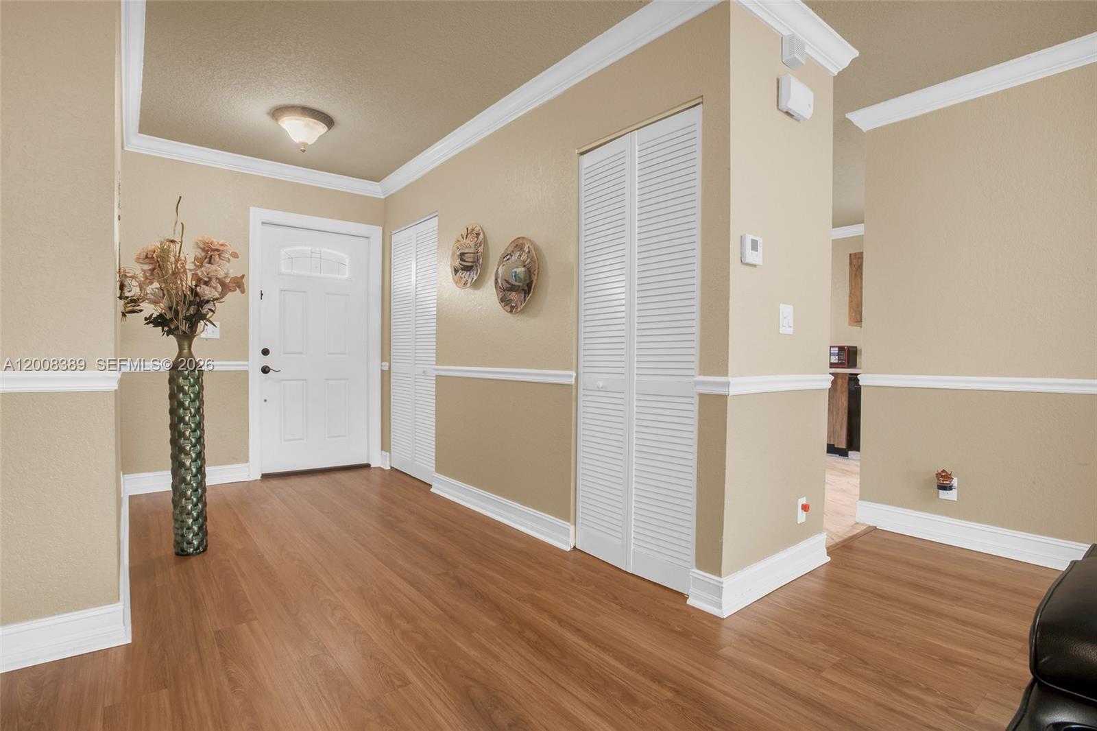 An entryway features wood-look flooring, beige walls with white wainscoting, and white louvered closet doors — 7471 SW 1st St, Margate FL 33068, MARGATE, FL