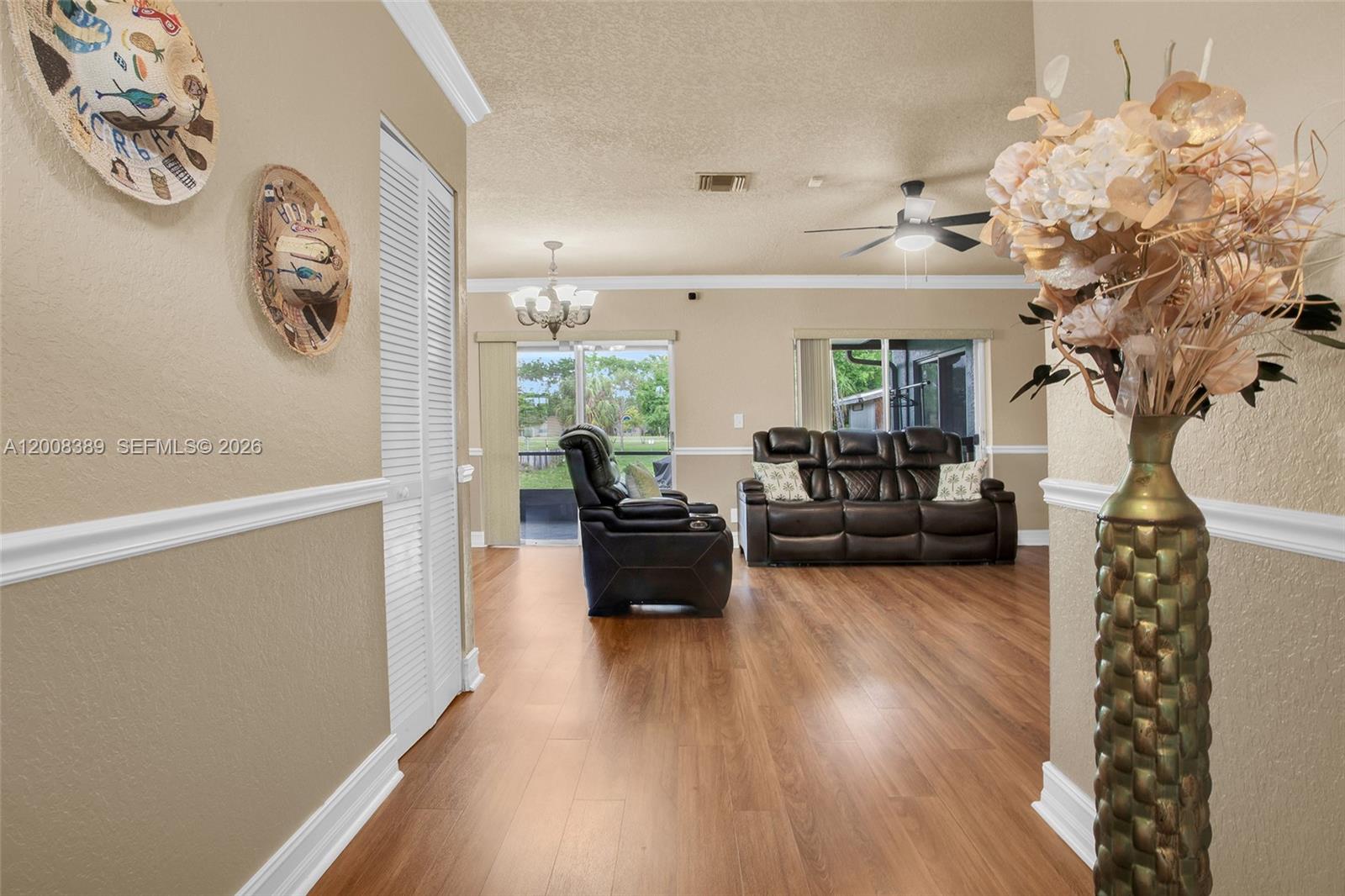 A living room features wood-look flooring, a ceiling fan, and a dark leather sofa set — 7471 SW 1st St, Margate FL 33068, MARGATE, FL