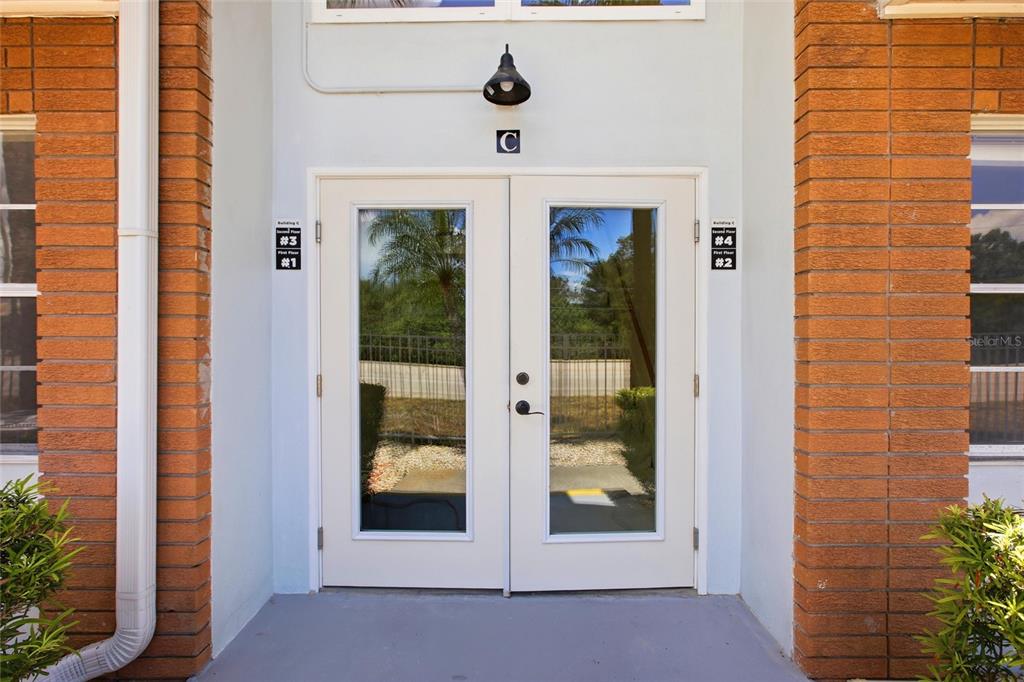 The exterior entrance to building C features double glass doors flanked by orange brick columns — 22333 EDGEWATER DRIVE UNIT C2, PUNTA GORDA, FL
