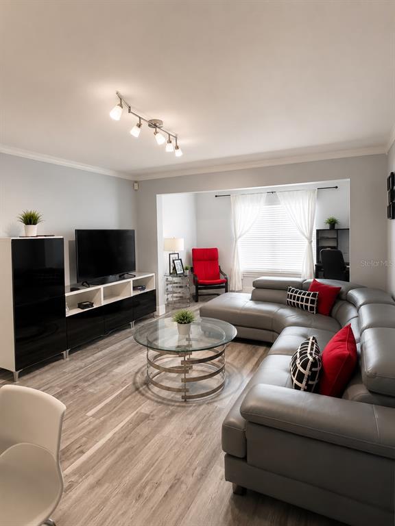 A living room features a grey sectional sofa, a glass coffee table, and a television console — 5463 VINELAND ROAD UNIT 5203, ORLANDO, FL