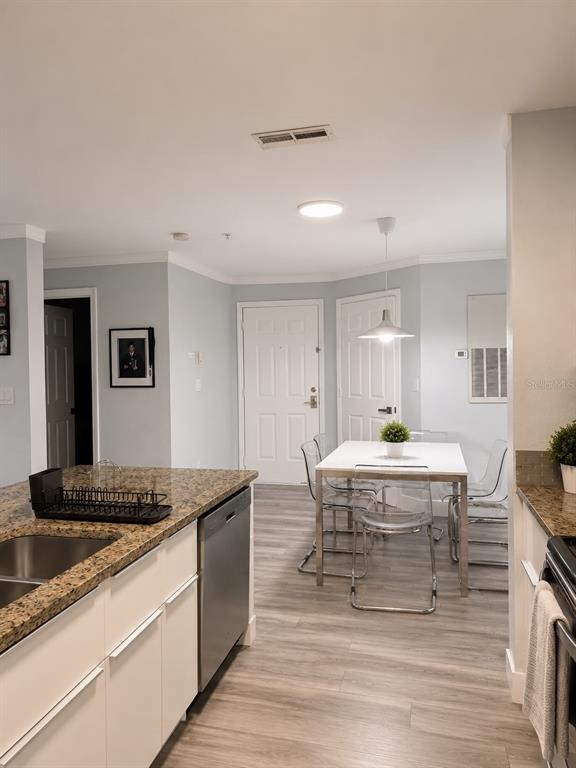 A kitchen with granite countertops and a dining area featuring a white table and chairs — 5463 VINELAND ROAD UNIT 5203, ORLANDO, FL