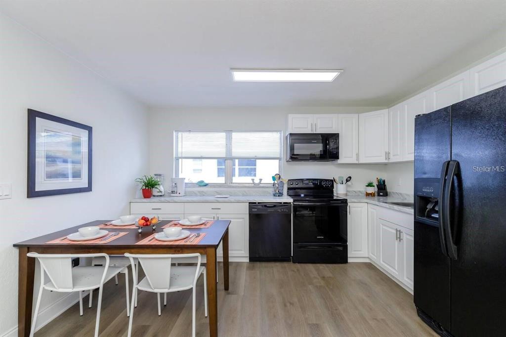 A kitchen with white cabinets, black appliances, and a dining table with four chairs — 1297 13TH STREET, SARASOTA, FL