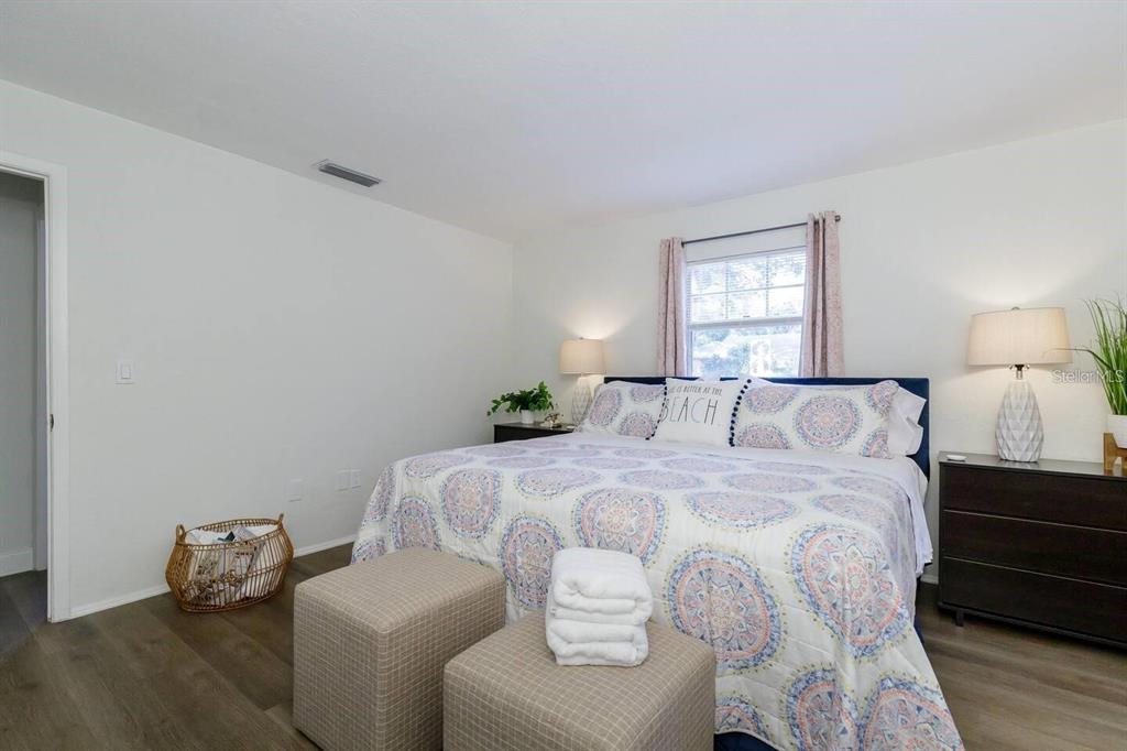 A bedroom features a bed with patterned bedding, two ottomans, and two bedside lamps — 1297 13TH STREET, SARASOTA, FL