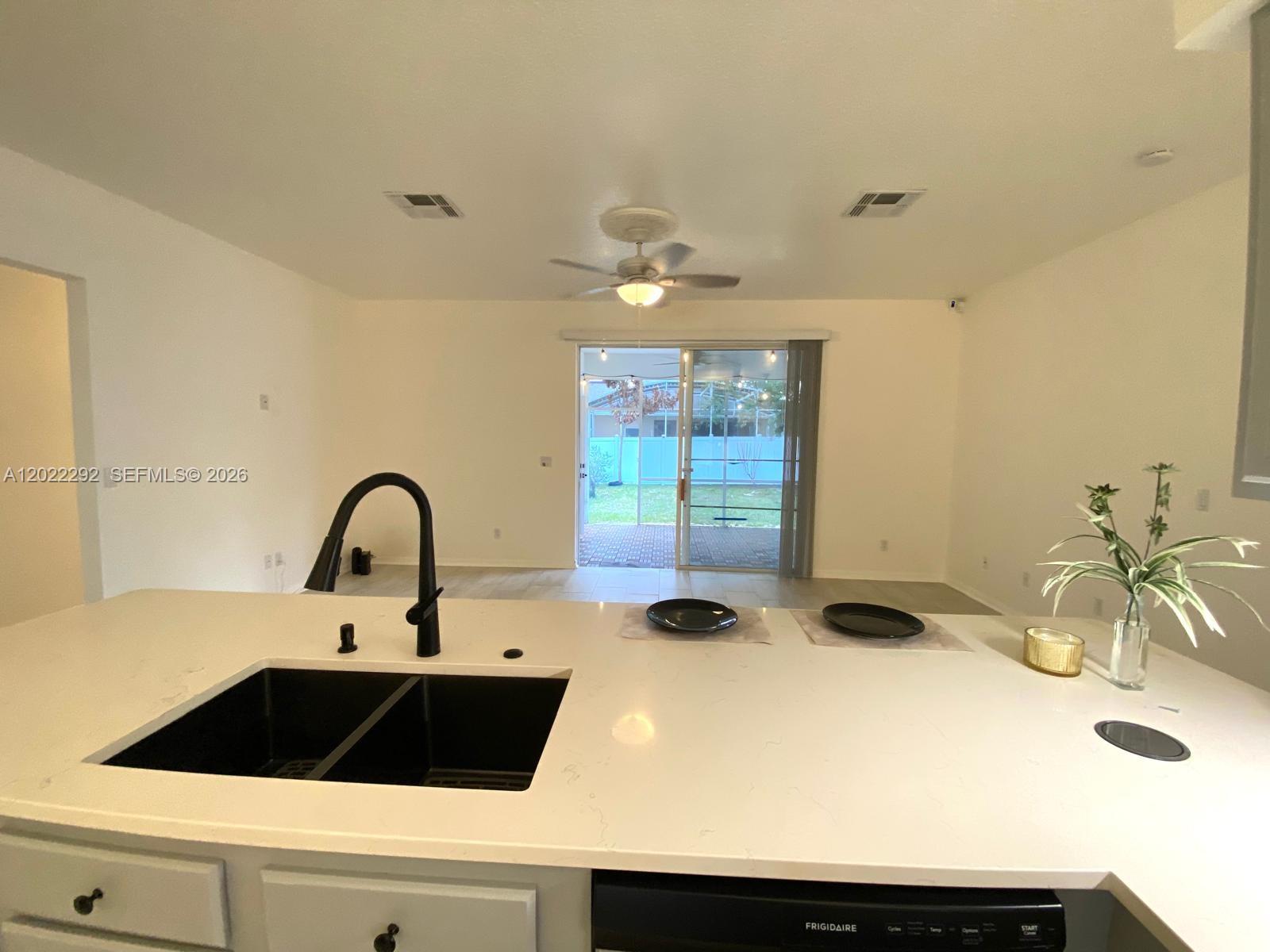 A kitchen island with a black sink overlooks a living area with sliding glass doors — 3837 FALLSCREST, Clermont FL 34711, CLERMONT, FL