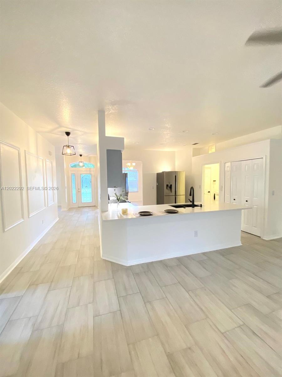 A kitchen with a white island and light-colored tile flooring opens into a living area — 3837 FALLSCREST, Clermont FL 34711, CLERMONT, FL