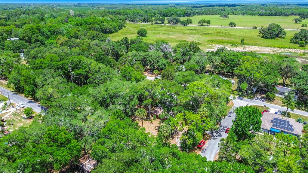 An aerial view shows a house nestled among trees near a road and open fields — 22736 SW 117TH STREET, DUNNELLON, FL