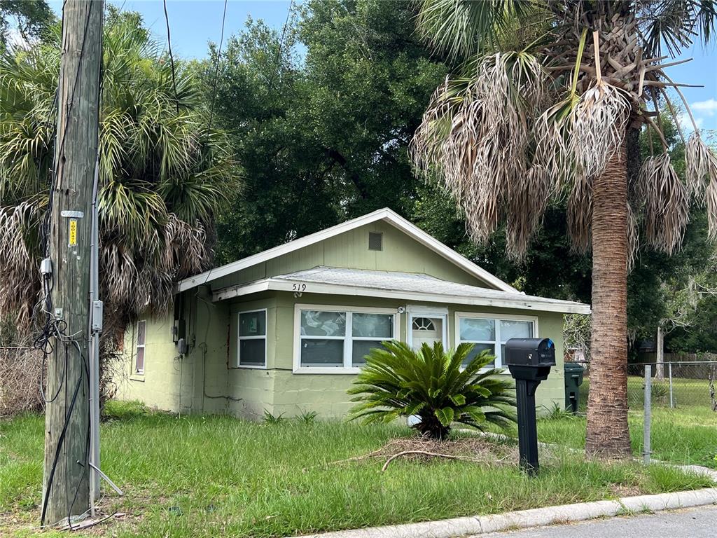A small, light green, single-story house with a front porch and palm trees — 519 W 12TH STREET, LAKELAND, FL
