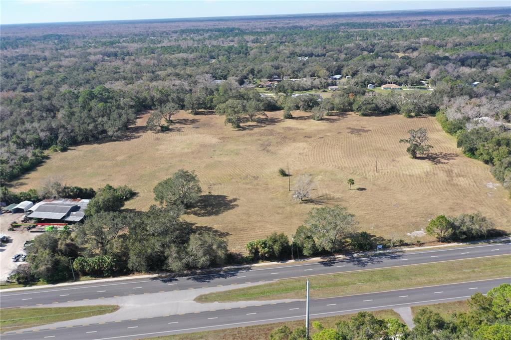 An aerial view shows a large, grassy vacant lot adjacent to a multi-lane highway — 4558 S RIDGEWOOD AVENUE, EDGEWATER, FL