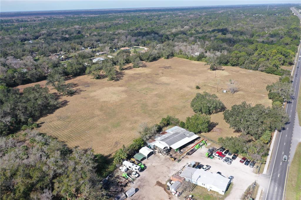 An aerial view shows a large, open grassy field adjacent to a commercial building — 4558 S RIDGEWOOD AVENUE, EDGEWATER, FL