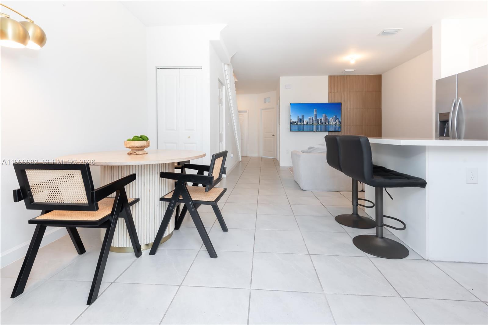A dining area with a round table and cane chairs sits beside a kitchen island — 9949 SW 228th Ter, Miami FL 33190, MIAMI, FL