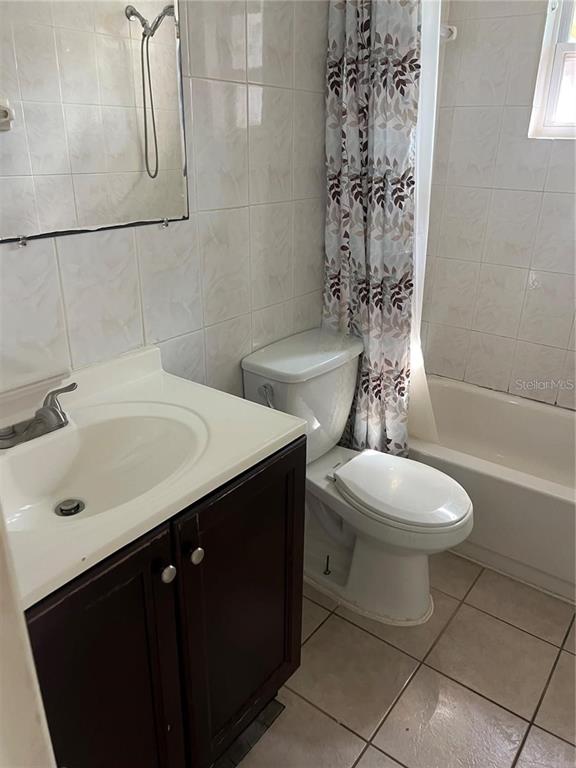 A bathroom features a vanity with a dark cabinet, a toilet, and a tiled tub — 7438 COVENTRY DRIVE, PORT RICHEY, FL